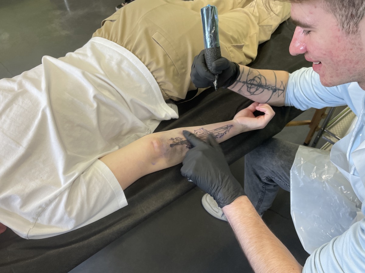 Fine line sword tattoo on forearm